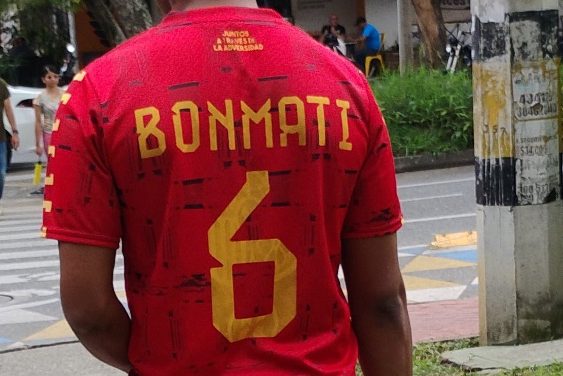Two people walking on a sidewalk with trees and street signs in the background